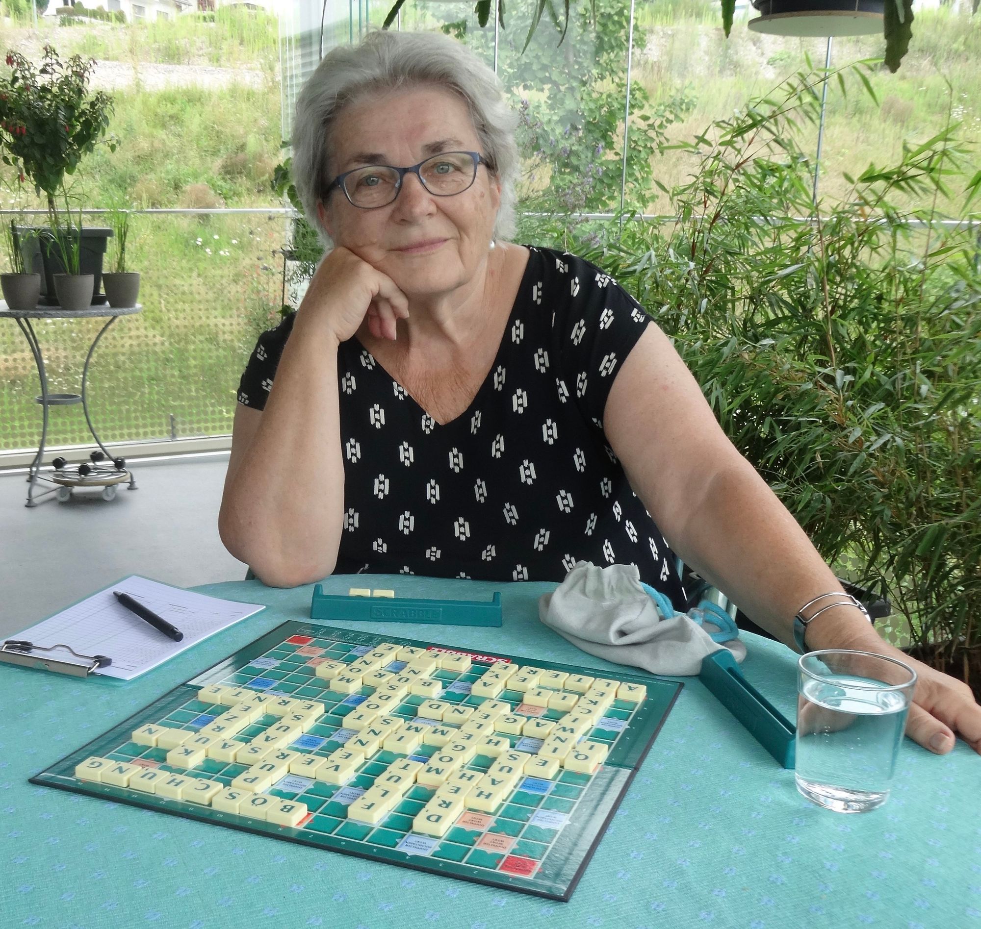 Regula Schilling Zahn‌ sitzt am Tisch vor einem Scrabble Spiel