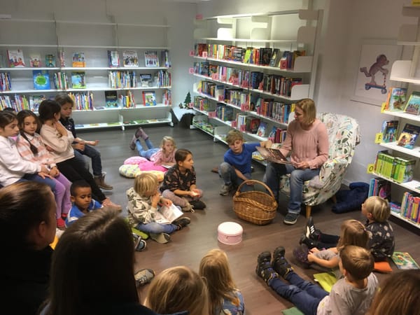 Kinder höhren zu, wie in der Bibliothek Schmerikon Adventsgeschichten erzählt werden